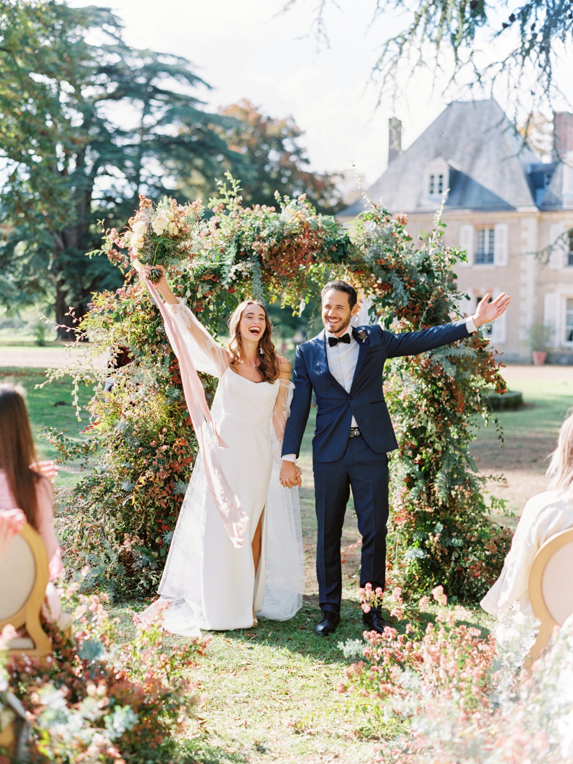 A bride and groom smile and throw their hands in the air after their ceremony in Paris, France.
