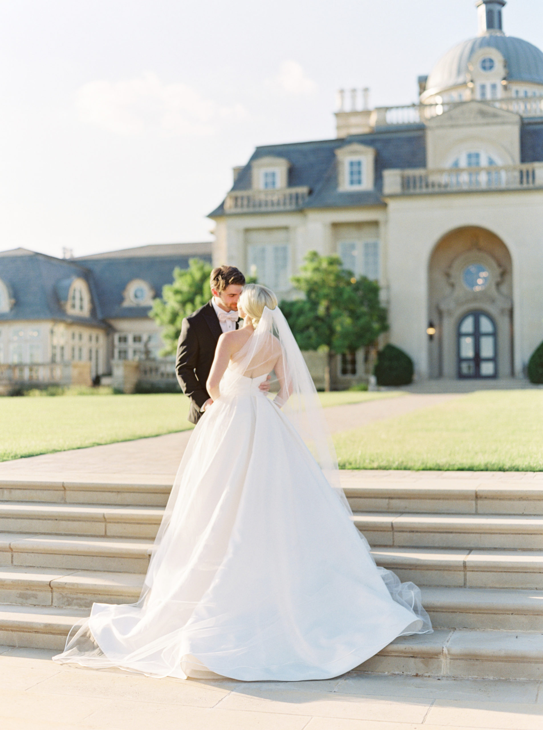 Bride and groom sharing a tight embrace as they stand on the stairs outside The Olana in Dallas, TX photographed by wedding photographer Mackenzie Reiter