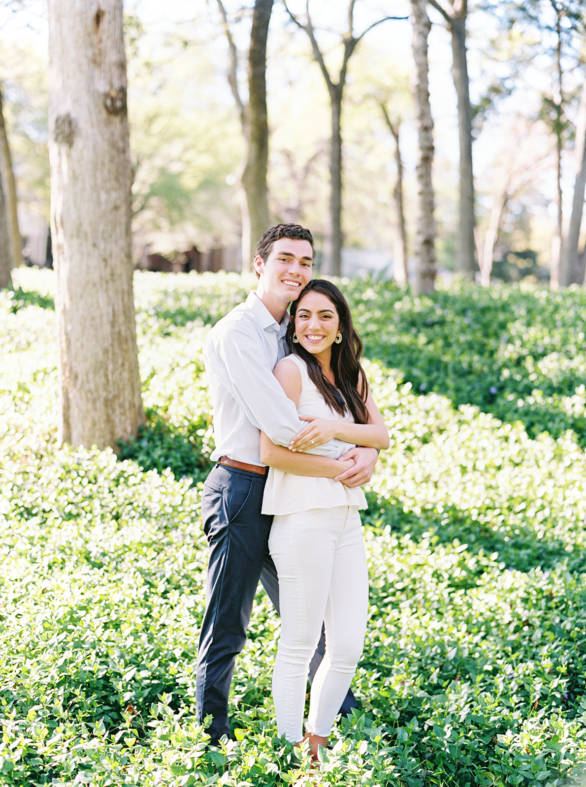Couple share a hug in the lush greenery at Prather & Flippen Park for their engagement shoot