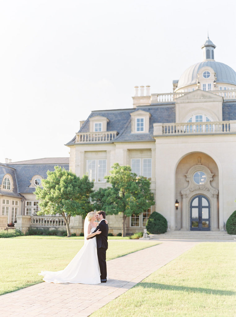 Bride and groom sharing an intimate hug in front of The Olana in Dallas, TX photographed by Mackenzie Reiter