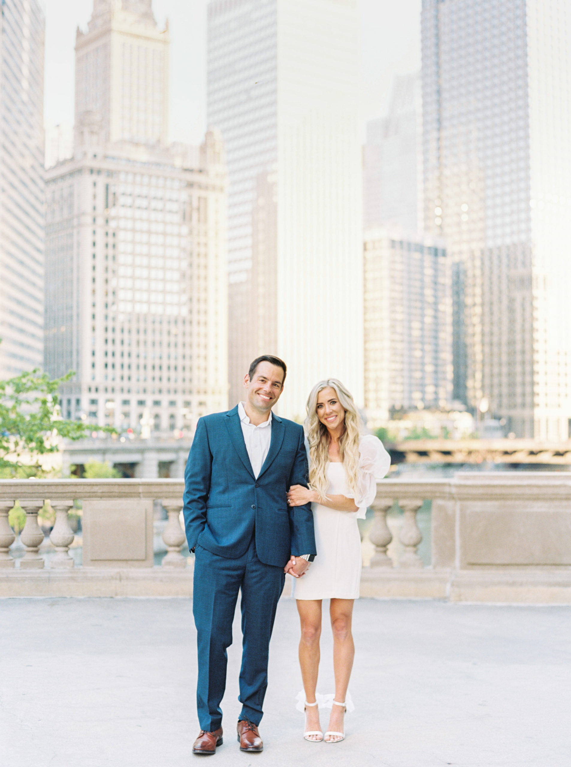 Engaged couple pose in front of a stunning view of the Chicago skyline during their classy upscale engagement session shot by Mackenzie Reiter