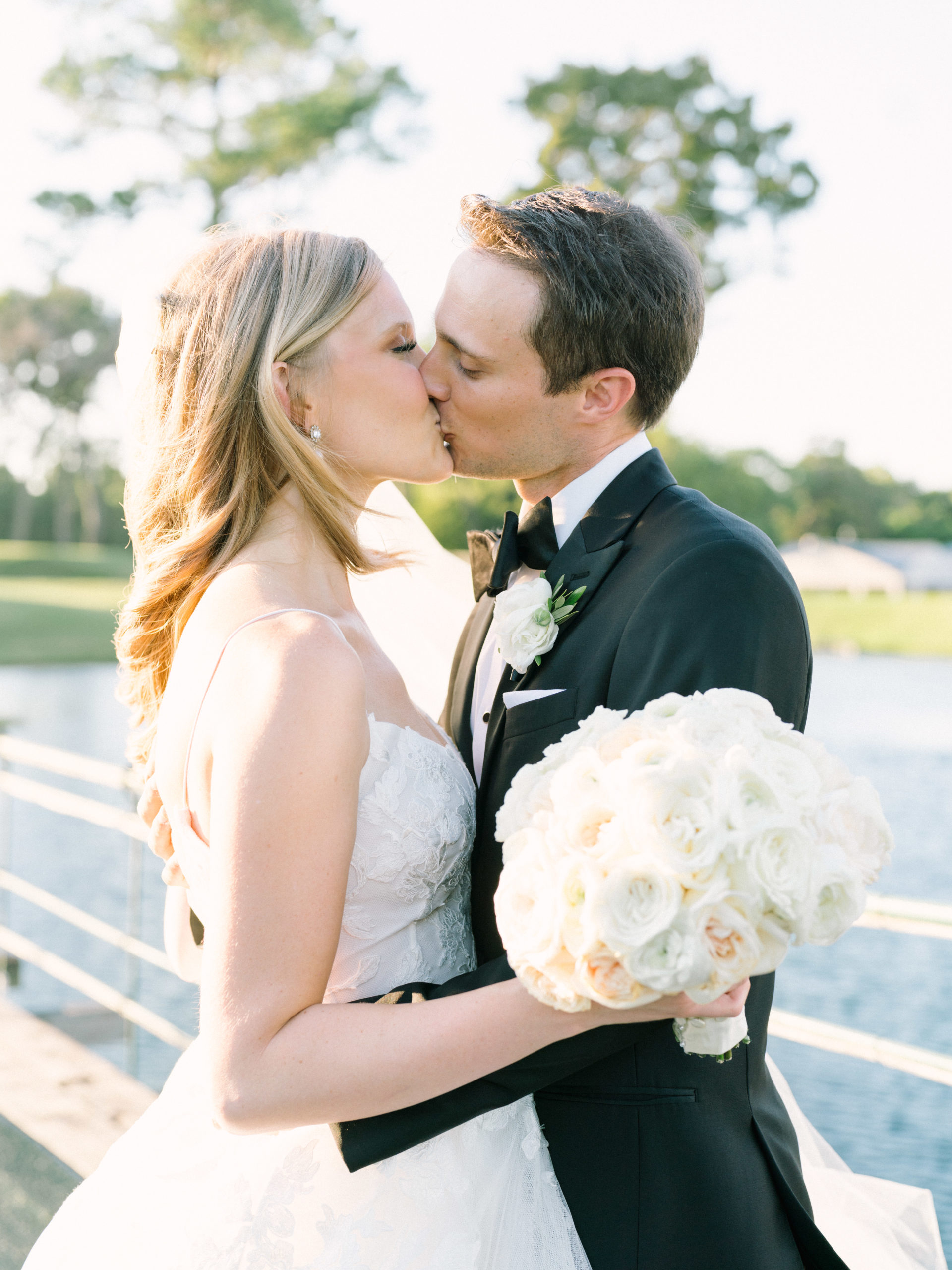Bride and groom share a kiss, with the bride holding her gorgeous bouquet, at the Lakeside Country Club