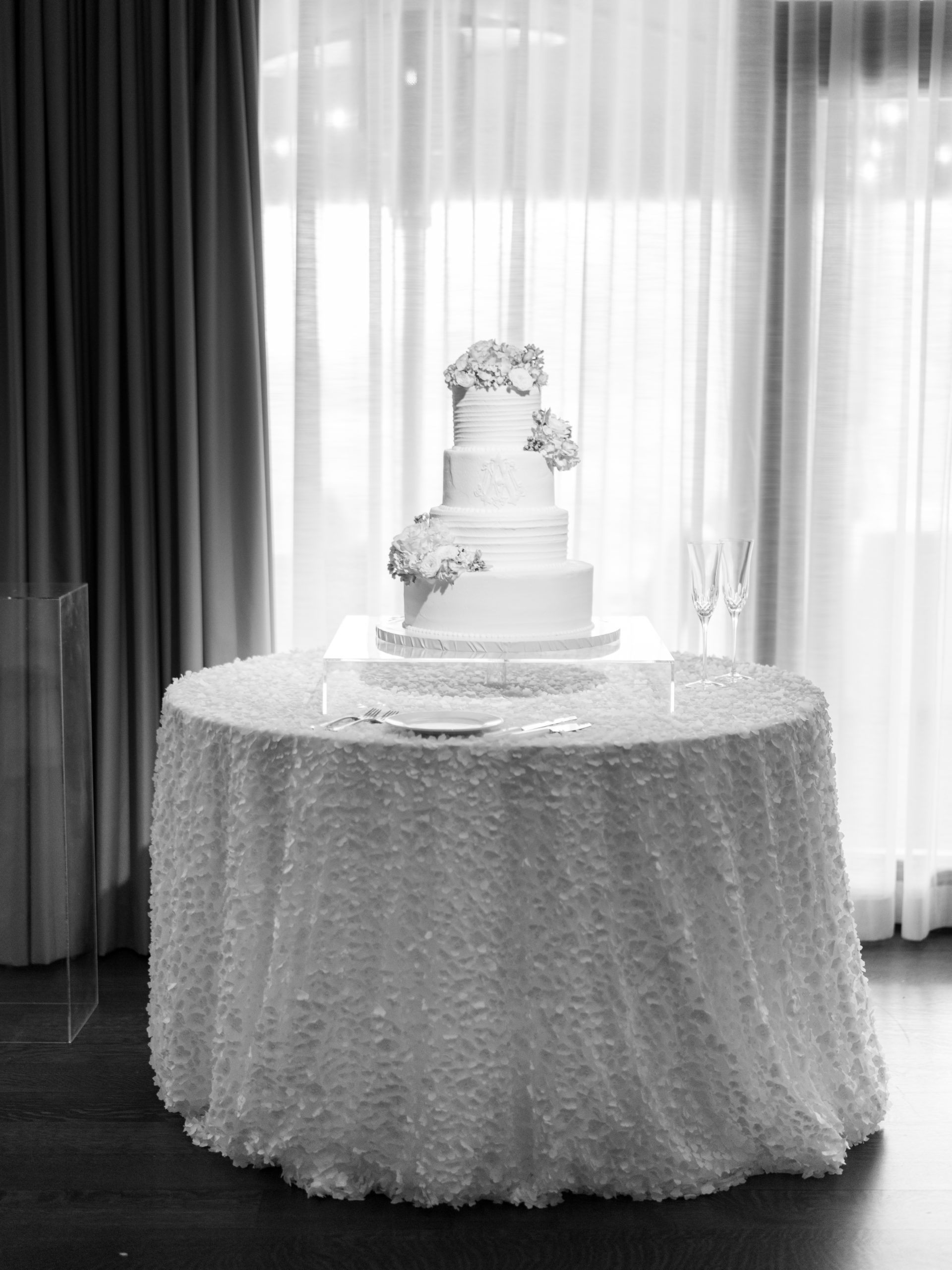 Black and white photo of the three-tier wedding cake placed on top of a round table